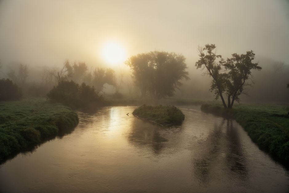Serene misty morning with the sun rising over a tranquil river bend in Tell, Wisconsin.