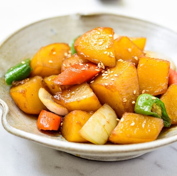 윤기 있게 졸여진 감자조림이 흰 접시에 담겨 있으며, 간장 양념이 고루 배어 부드럽고 달콤짭짤한 전통 한식 반찬의 모습.