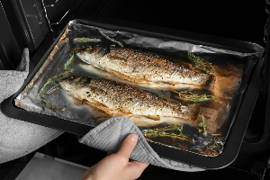 고등어 두마리를 구워 오븐에서 꺼내고 있다