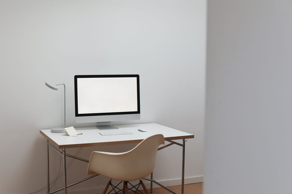 Interior of room in minimal design with modern computer on white table and comfortable chair