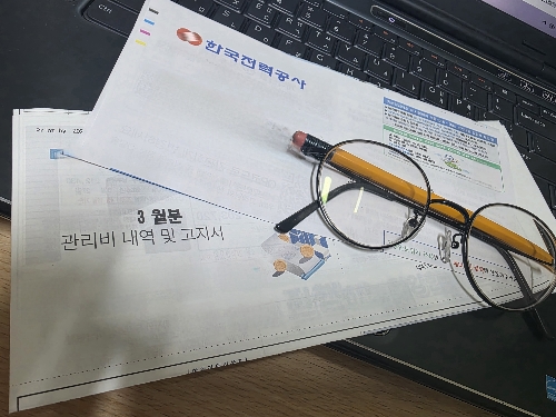 전기요금 고지서와 안경을 통해 공과금 절약을 확인하는 모습