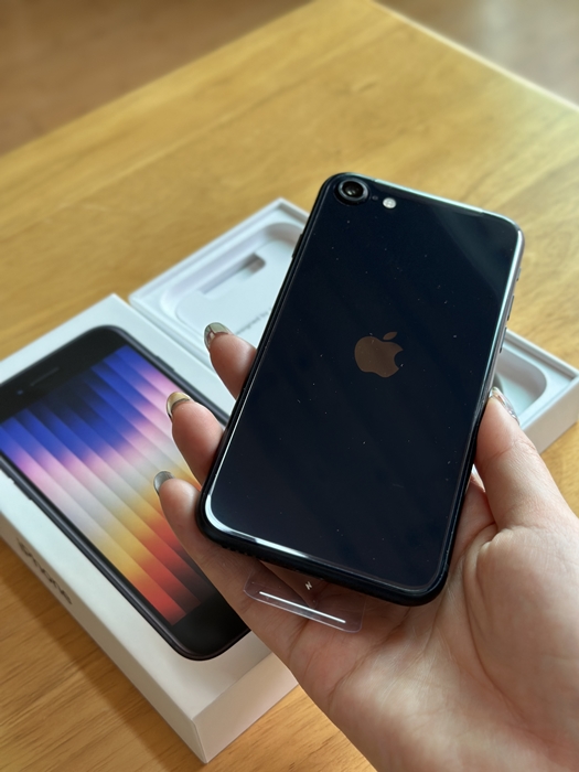 손에 들고 있는 아이폰 SE3 블랙 색상 본체 뒷면&amp;#44; 애플 로고와 카메라가 선명하게 보이는 모습