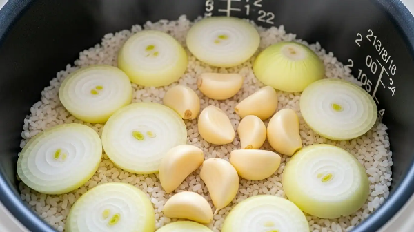 전기밥솥에 마늘과 양파를 함께 넣고 밥을 하는 모습