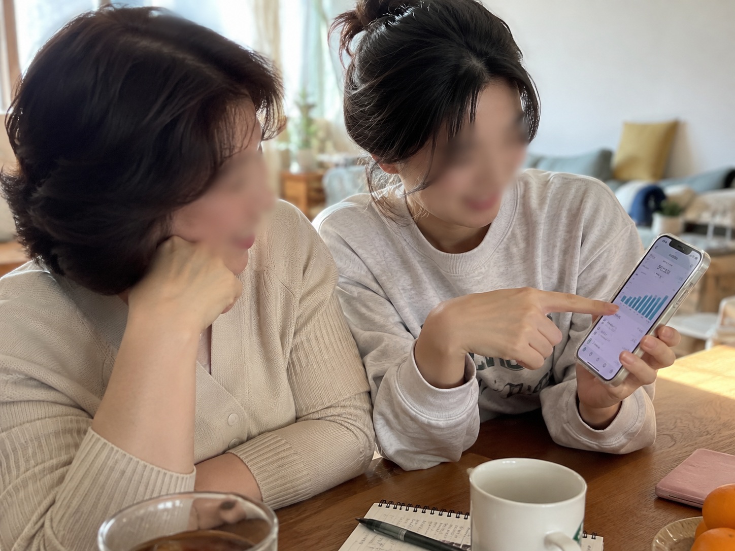 청년미래적금 가입 조건을 알아보기 위해 엄마와 20대 딸이 스마트폰 금융 화면을 함께 살펴보는 모습