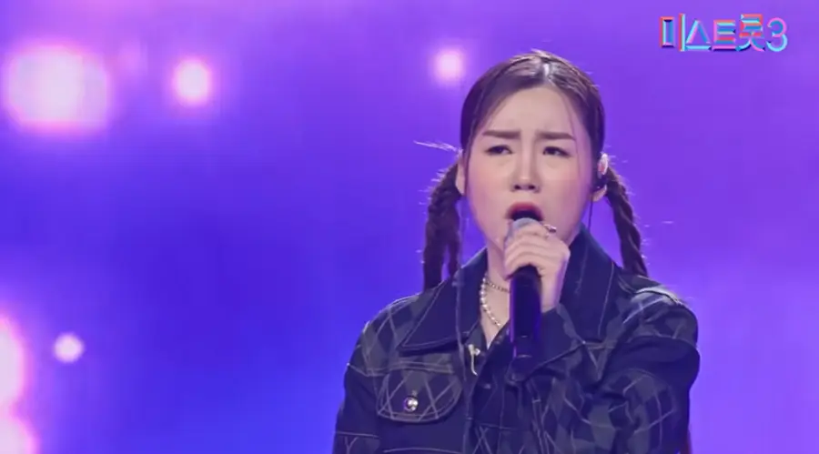 미스트롯3- 검은색 쟈켓을 입고 머리를 양갈래로 땋고 왼손으로 마이크를 잡고 진지한 눈으로 노래하는 나영