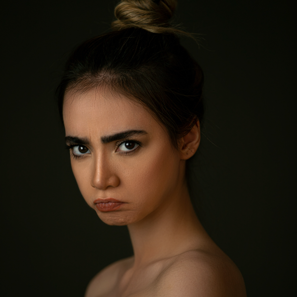 한 여성이 입술을 내밀고 불만 가득한 표정으로 이쪽을 바라보는 사진