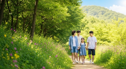 가족이 산책로를 걷는 모습&amp;#44; 배경은 초록 숲과 햇살