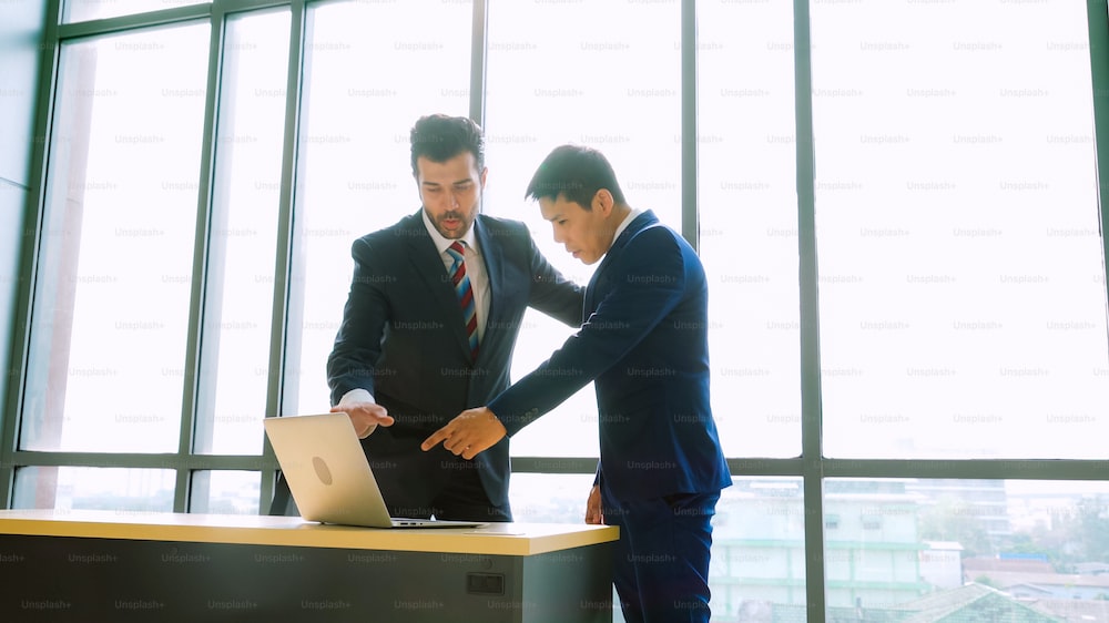 양복 입은 남성둘이 노트북을 보며 서로 협상중이다