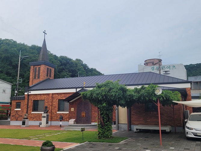 새방골성당 사진입니다. 사진 속에 흉상은 김보록 신부님을 표현한 것이고 흉상과 성전 출입문 사이에 순례확인도장을 찍을 수 있는 작은 함이 설치되어 있습니다.