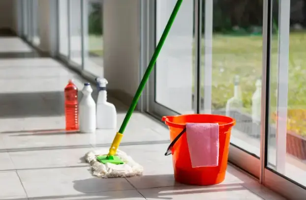 베란다 바닥을 청소하기 위한 대걸레, 빨간 청소통, 세정제가 놓여 있는 모습