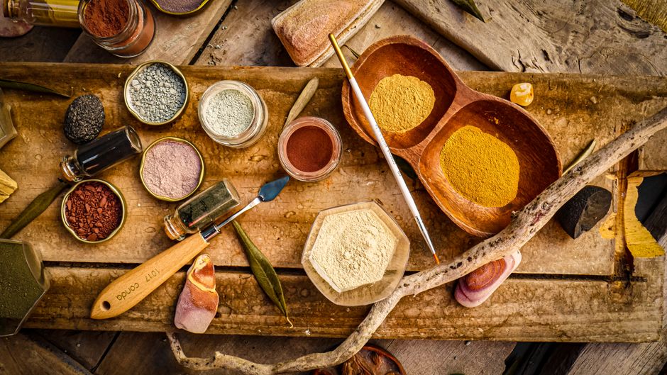 Explore a variety of natural pigments and tools on a rustic wooden surface for artistic projects.