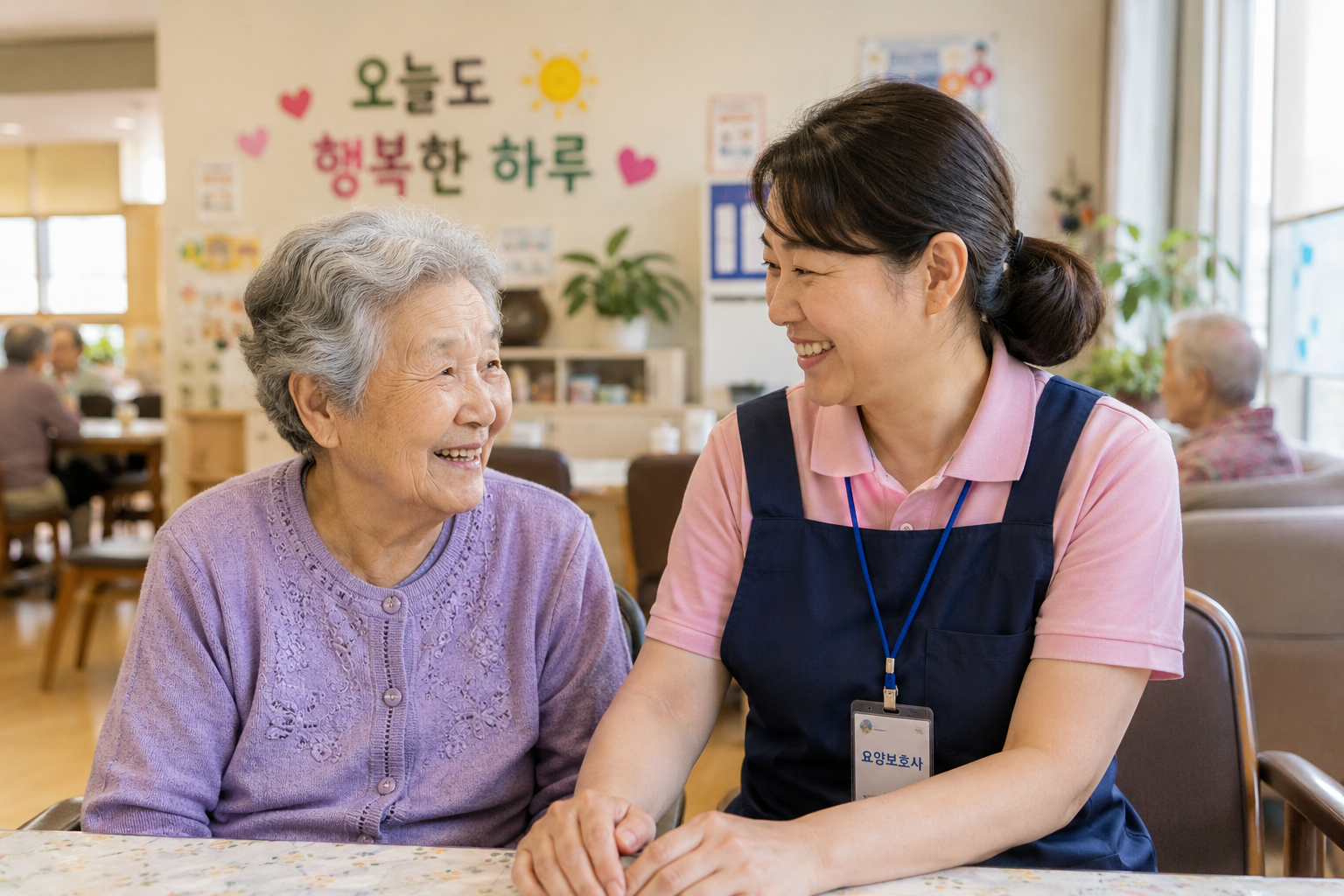 어머니와 같은 주야간보호센터에서 여성 요양보호사가 어르신과 따뜻하게 손을 맞잡고 대화하는 모습