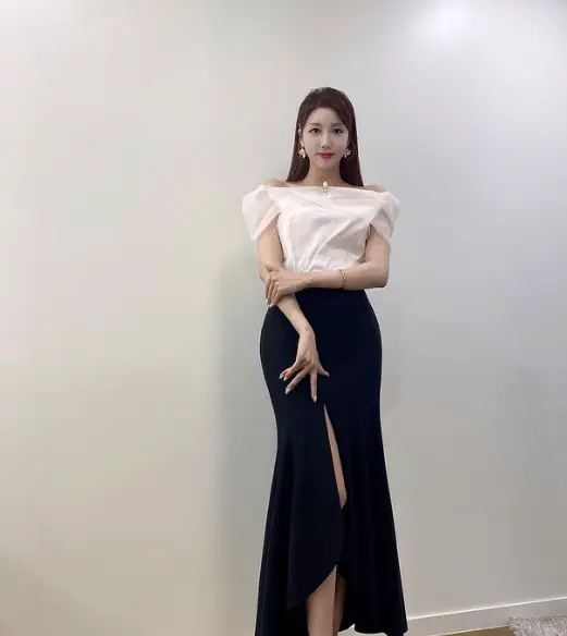 현역가왕- 흰색 반팔 블라우스를 입고 한쪽 다리가 파인 롱스커트를 입고 서있는 두리