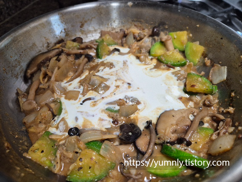 Adding liquid heavy cream to the mixture of soybean paste and vegetables in the frying pan
