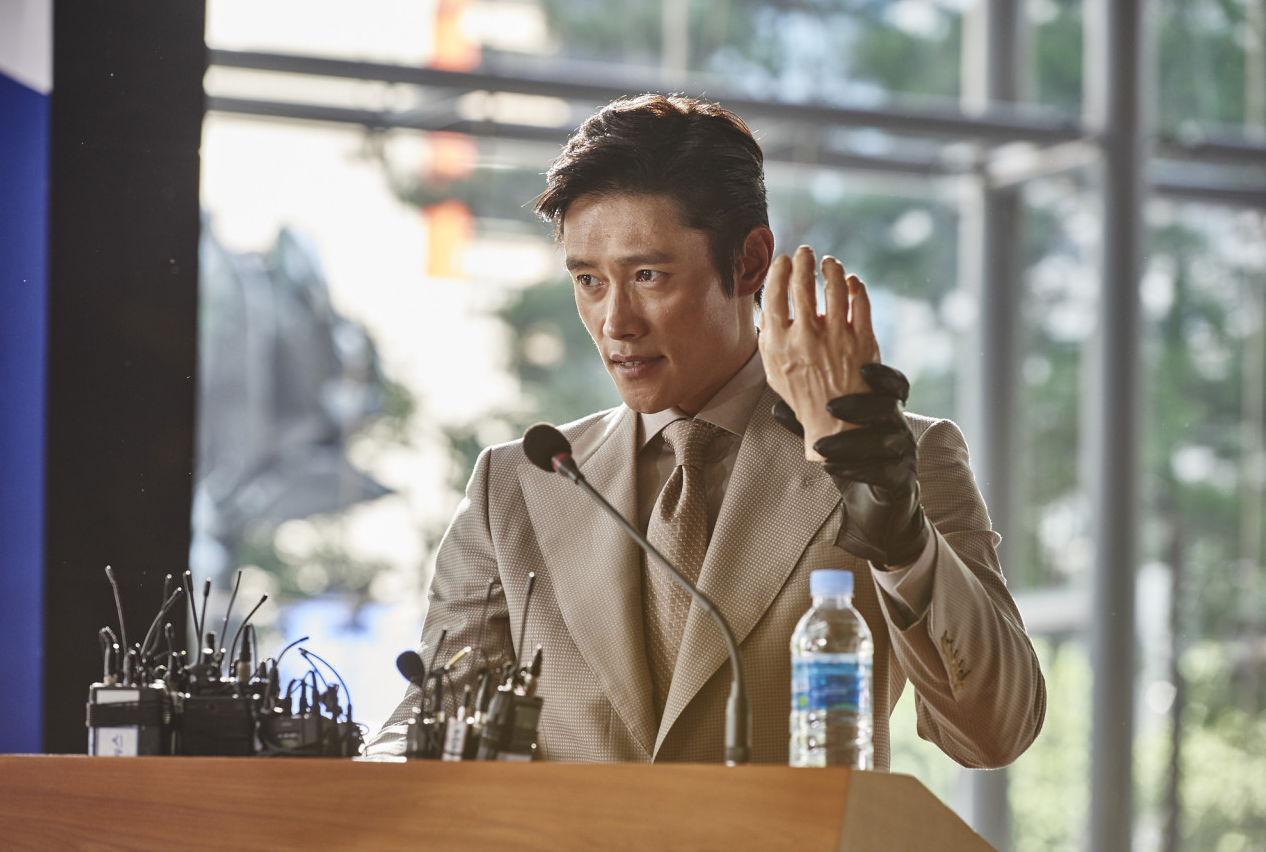 기자회견장 단상에 선 안상구가 한 손에 검은 장갑을 낀 채 옆을 바라보고 있는 장면