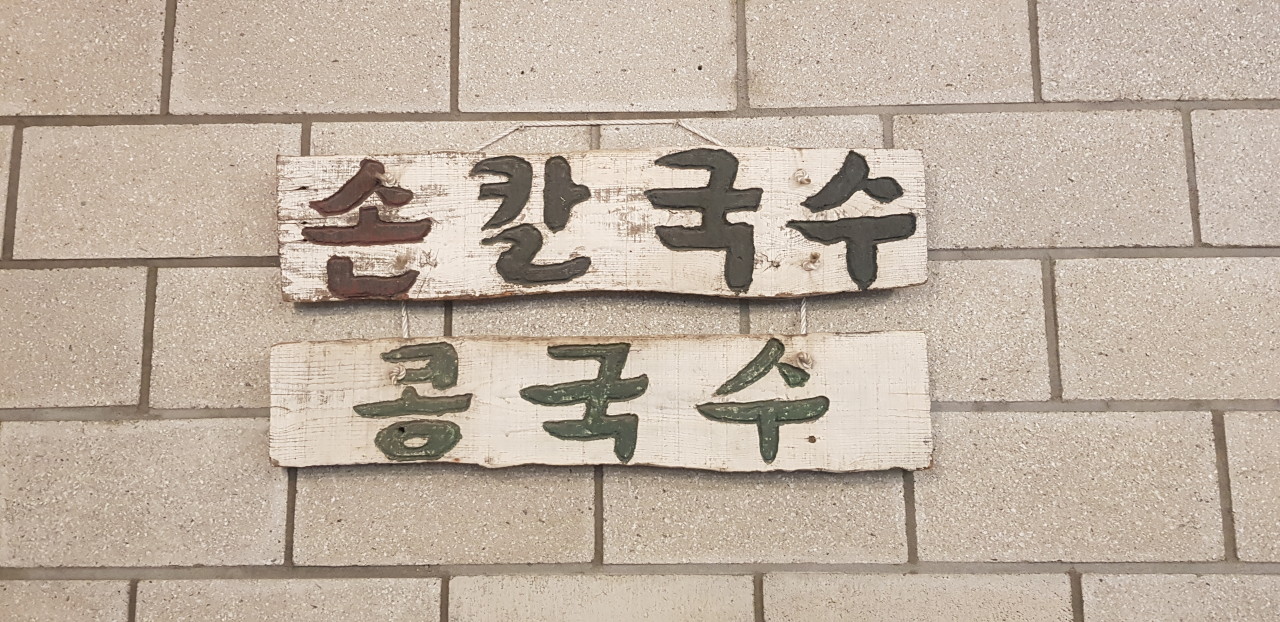 사진 속에서도, 실제 벽면에서도 빛을 발하는 낡은 나무 명패. 이곳의 살아있는 역사입니다.