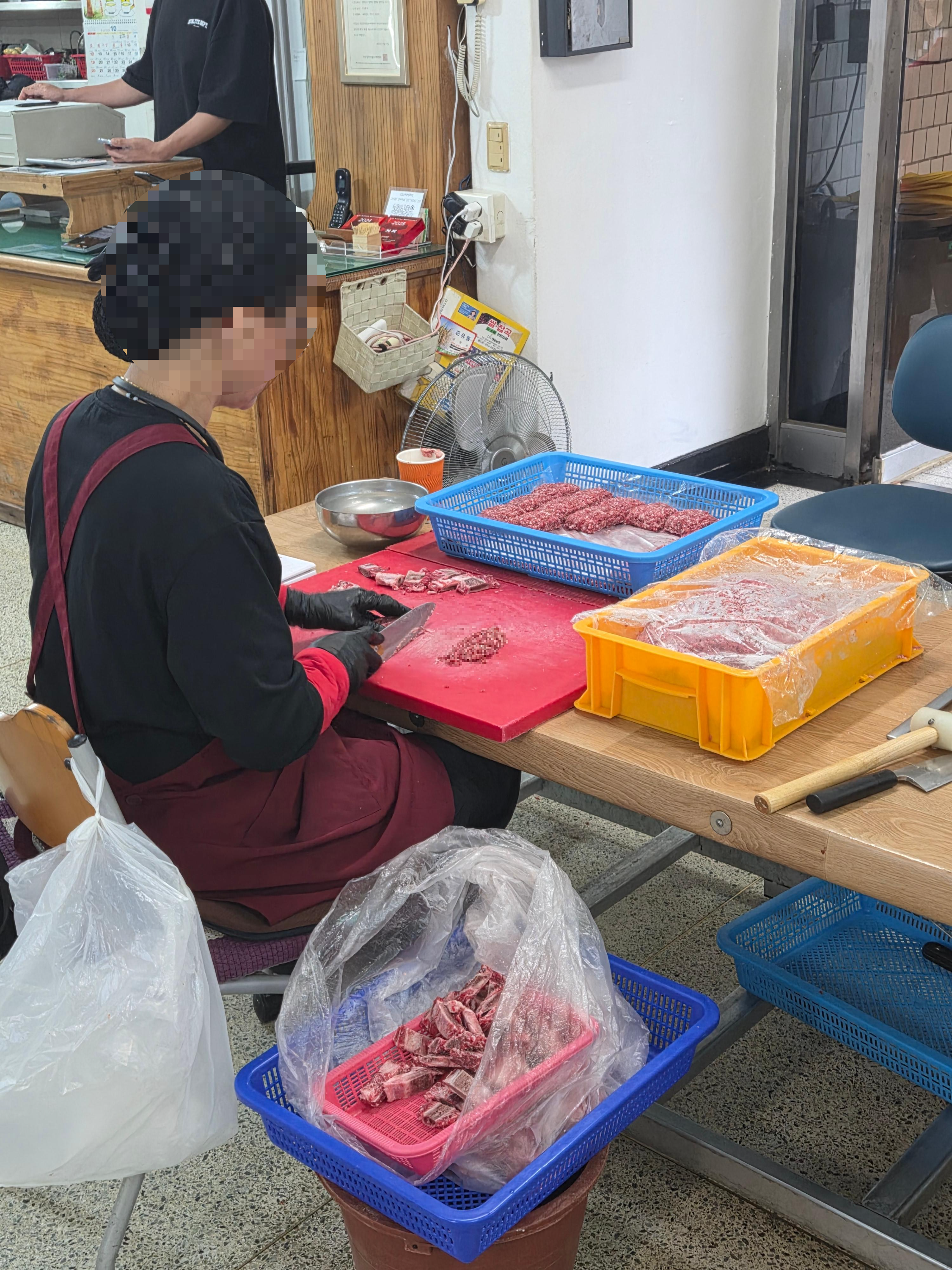 신식당 내부에서 한 직원이 한우 갈비살을 손질하는 모습