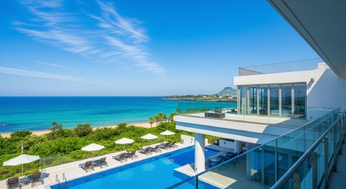 제주 해변 근처 리조트 외관&amp;#44; 푸른 바다와 밝은 하늘&amp;#44; 여름