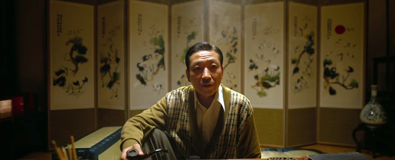 병풍을 배경으로 담배 곰방을 쥐고 있는 경성크리처에서 준택 아버지 역의 배우 최광일