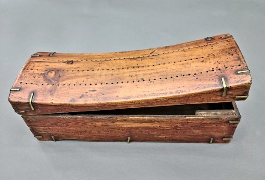 잣나무를 깎아서 만든 베개인 신침을 원형 그대로 회색 바닥 위에 놓아두고 찍은 사진