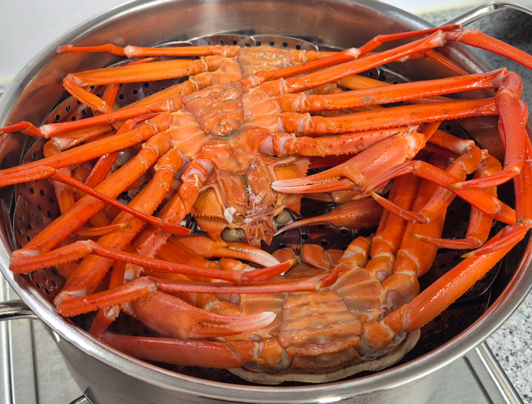 스텐 찜기에 홍게 세 마리를 배가 위로 향하게 (등딱지가 아래로) 안착시킨 모습. 다리가 찜기 밖으로 뻗어 있다.