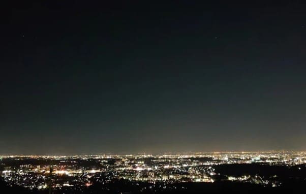 야간의 하늘 밑으로 도시의 전경 불빛들이 보인다.