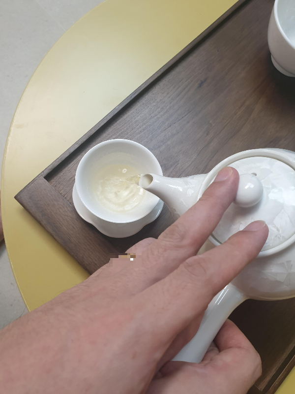 다완 뚜꺼을 손가락으로 잡고 찻 물을 붓고 있다.