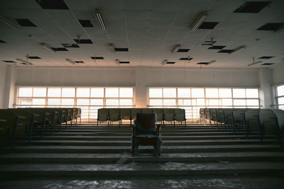 Desolate lecture hall with empty seating, displaying a sense of abandonment and neglect.