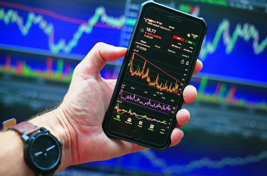 미국 주식 차트가 띄워 진 핸드폰을 쥔 남자 손