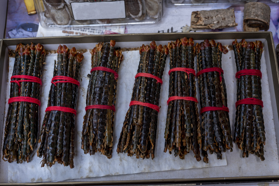 지네를 잡아서 깨끗하게 세척하고 말린 것을 한움큼씩 붉은 색의 실로 묶은 것을 7덩이를 가판에 놓아둔 것을 찍은 사진