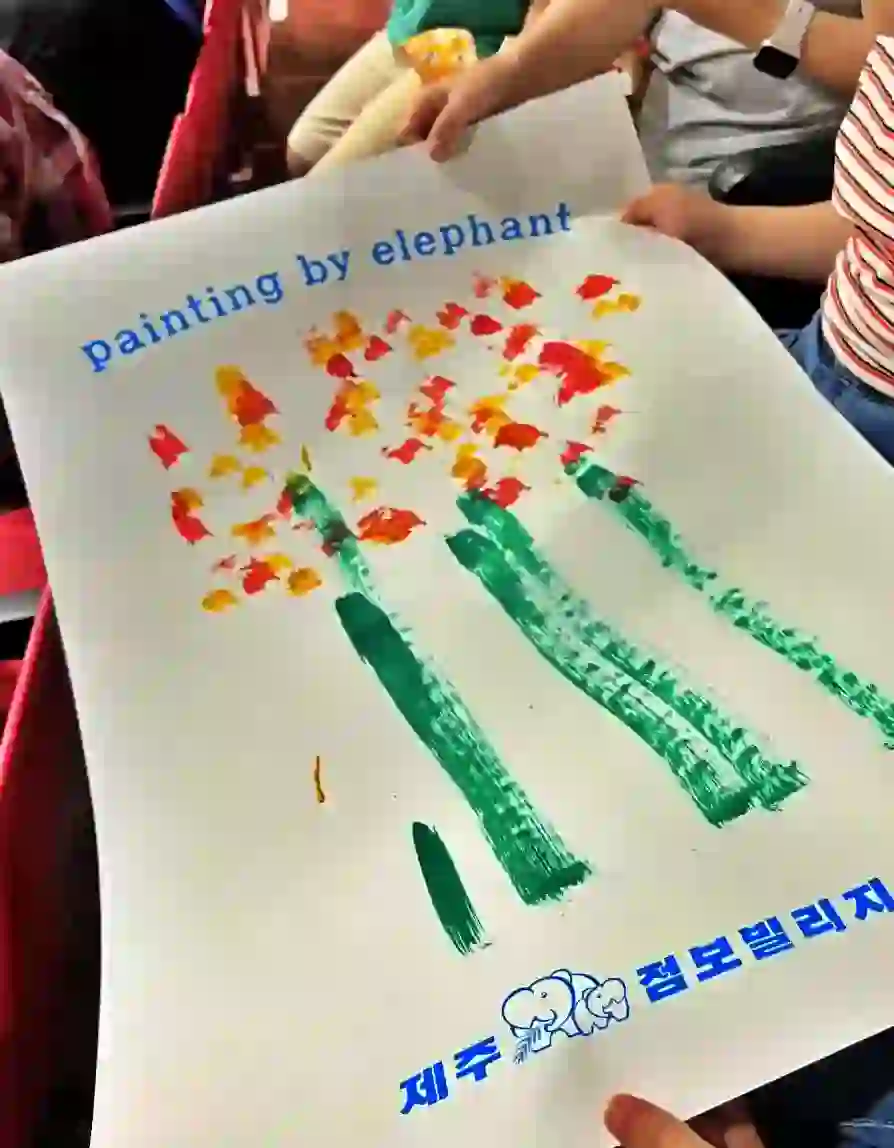 코끼리가 그린 그림을 받고 가족들이 좋아하는 상황입니다.