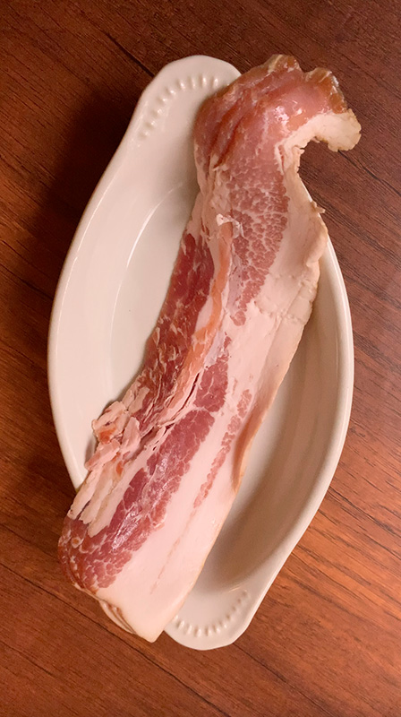 흰색의 긴 접시에 담긴 베이컨