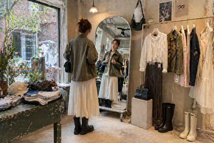 서울 편집숍 안에서 대비감 있는 아이템을 고르는 소비자와 진열된 상반 조합 아이템들