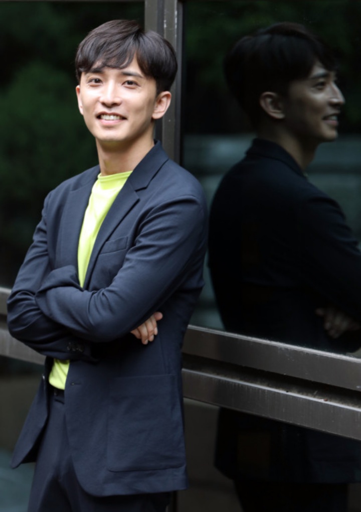 윤나무가 자신의 모습이 비치는 유리 앞에서 팔짱끼고 포즈를 취하고 있는 모습