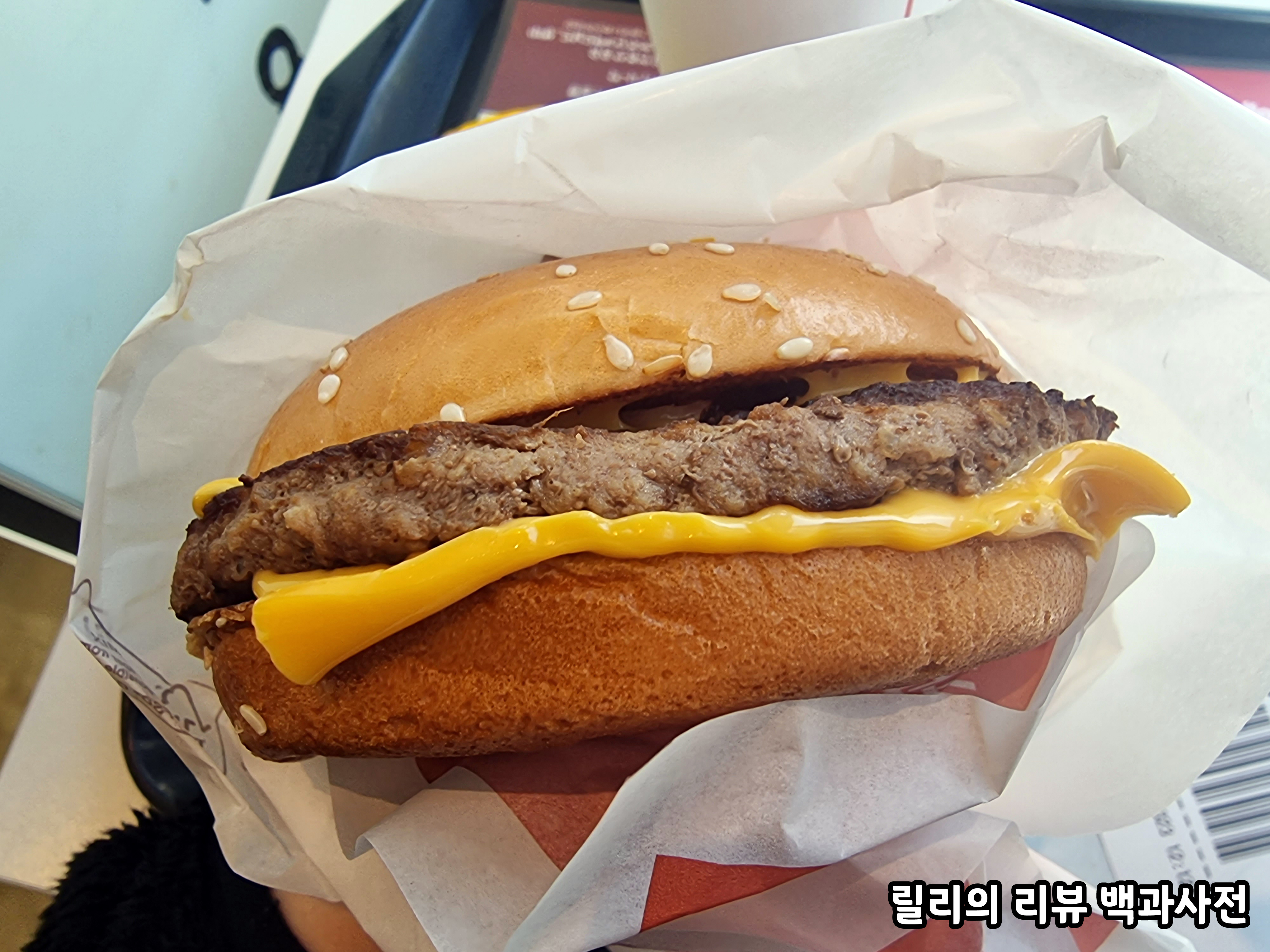 쿼터파운더 치즈버거의 사진. 빵 사이에 고기와 치즈 두 장이 있다.