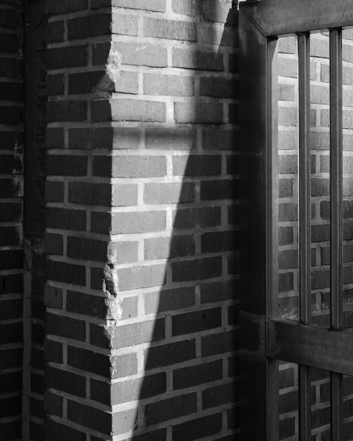 벽돌 벽 앞에 주변 조형물로 인해 삼각형의 모양만 햇빛이 비추고 나머지는 그림자가 만들어졌다. 흑백사진으로 둘 간의 대비가 잘 표현된 사진이다.