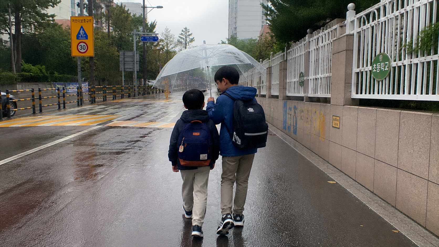 비 오는 날 우산을 함께 쓰고 등교하는 형제