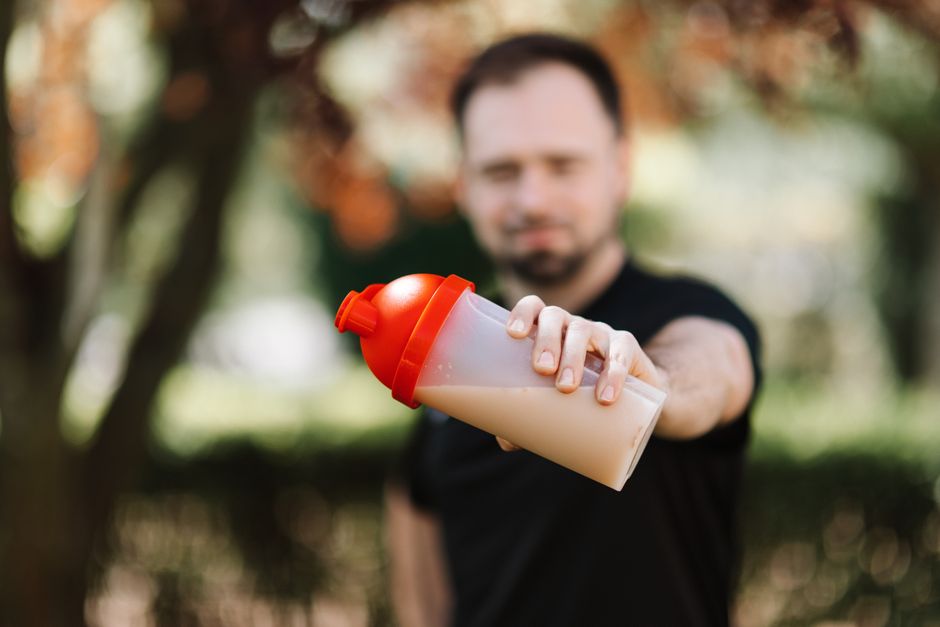 Korean Asian man taking supplements with water before workout at gym