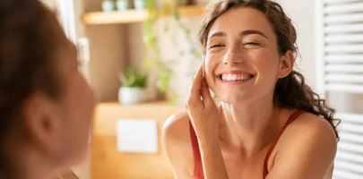 거울속 여성이 자신의 볼을 한손으로 잡고 활짝웃고있는 사진