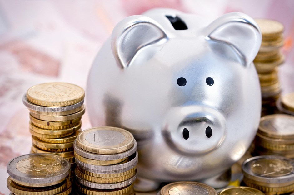 돼지 저금통 주변에 외국 동전이 있는 사진