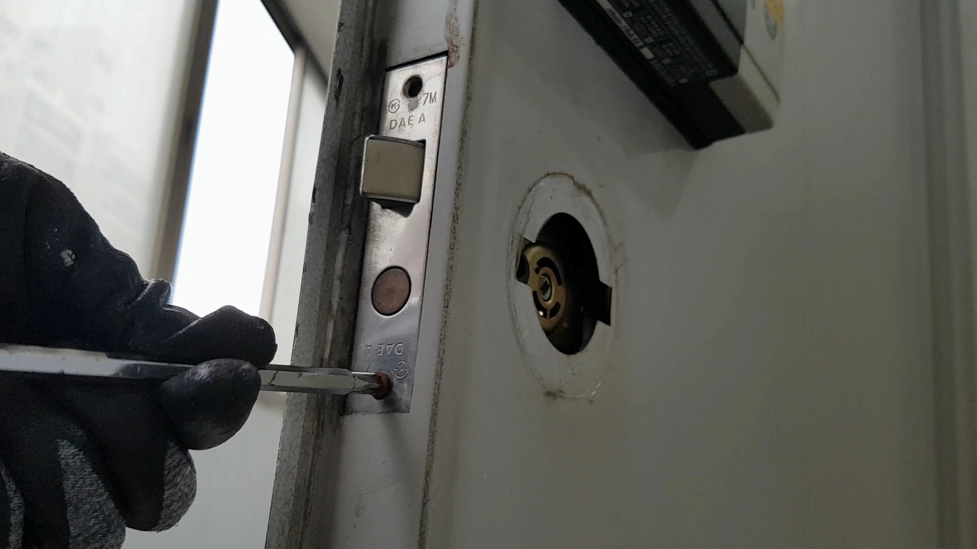 현관문 옆면 손잡이 부품 고정 볼트 푸는 모습