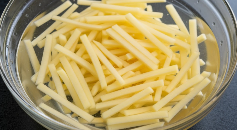 채 썬 감자를 찬물에 담가두어 전분기가 빠져나와 물이 뿌옇게 변한 모습