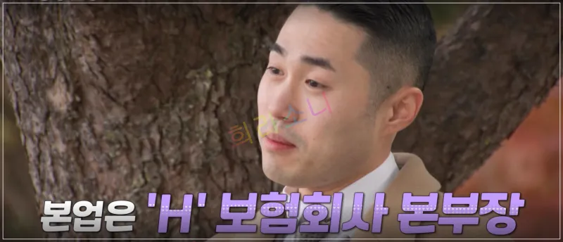 영수가 야외에서 나무 앞에 서서 미소를 지으며 인터뷰를 하고 있다. 그는 짧은 머리 스타일에 베이지색 코트를 입고 있다. 화면 하단에는 자막이 표시되어 있다. 자막: 