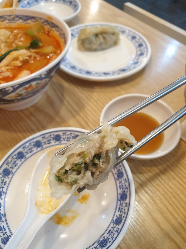 만두를 반으로 쪼개 속을 보여주고 있다. 육즙이 숟가락에 떨어진다.