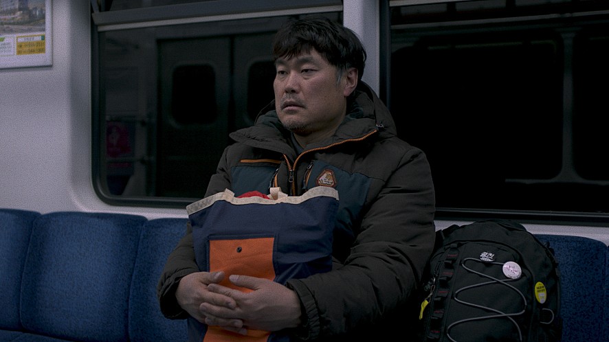 지하철에 앉아 있는 재복의 모습