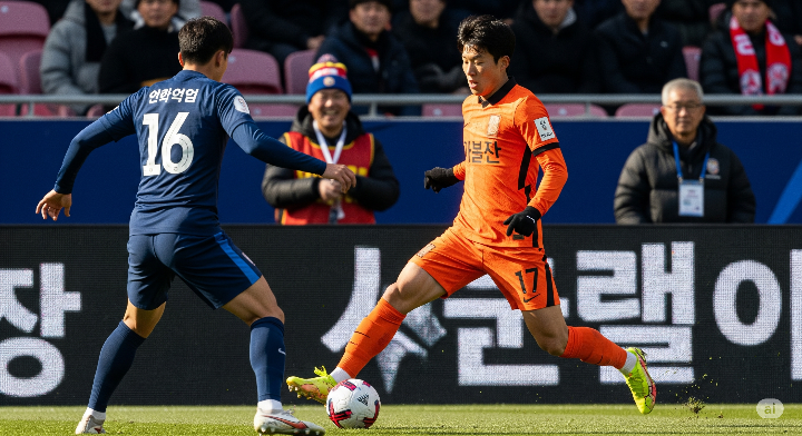 젊은 한국 축구 선수가 드리블하며 상대 수비수를 제치는 역동적인 모습