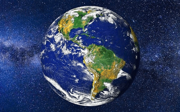 우주 안에 떠 있는 둥그런 지구가 있다. 우주는 푸른색이고 별들이 많다. 지구엔 초록색과 갈색으로 칠해진 아메리카 대륙이 보인다.