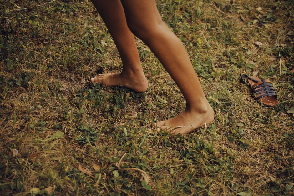 Close-up of a person walking barefoot on grass, conveying relaxation and freedom.