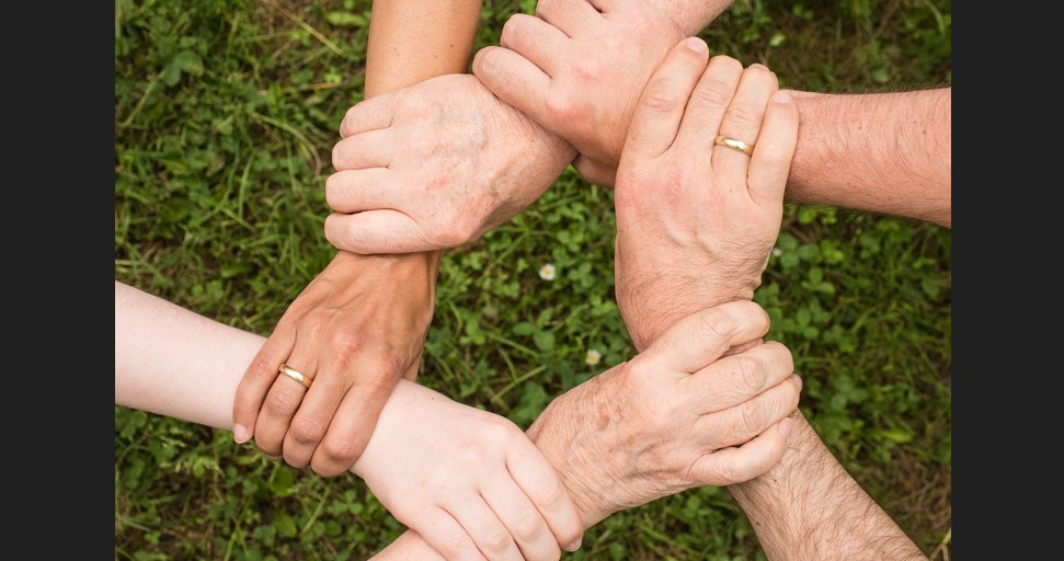 6명이 각자의 손으로 서로의 손목을 6 각형모양으로 연결되게 이어 잡고 있다.
