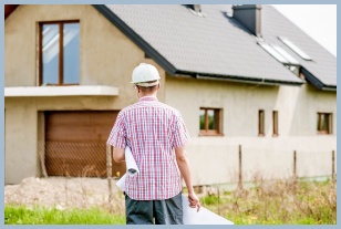 주택 앞 도면을 들고 서있는 남자